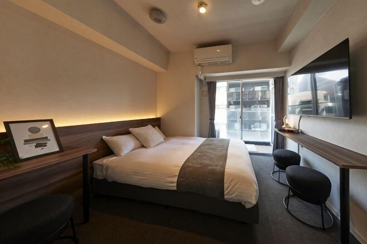 Une chambre d’hôtel moderne, dotée d’un grand lit, d’un bureau, d’une chaise, d’une télévision et d’une fenêtre offrant une vue agréable.