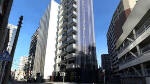 A modern high-rise building with multiple balconies and a pedestrian crossing sign. - Residence Hotel Hakata 20 (Fukuoka)