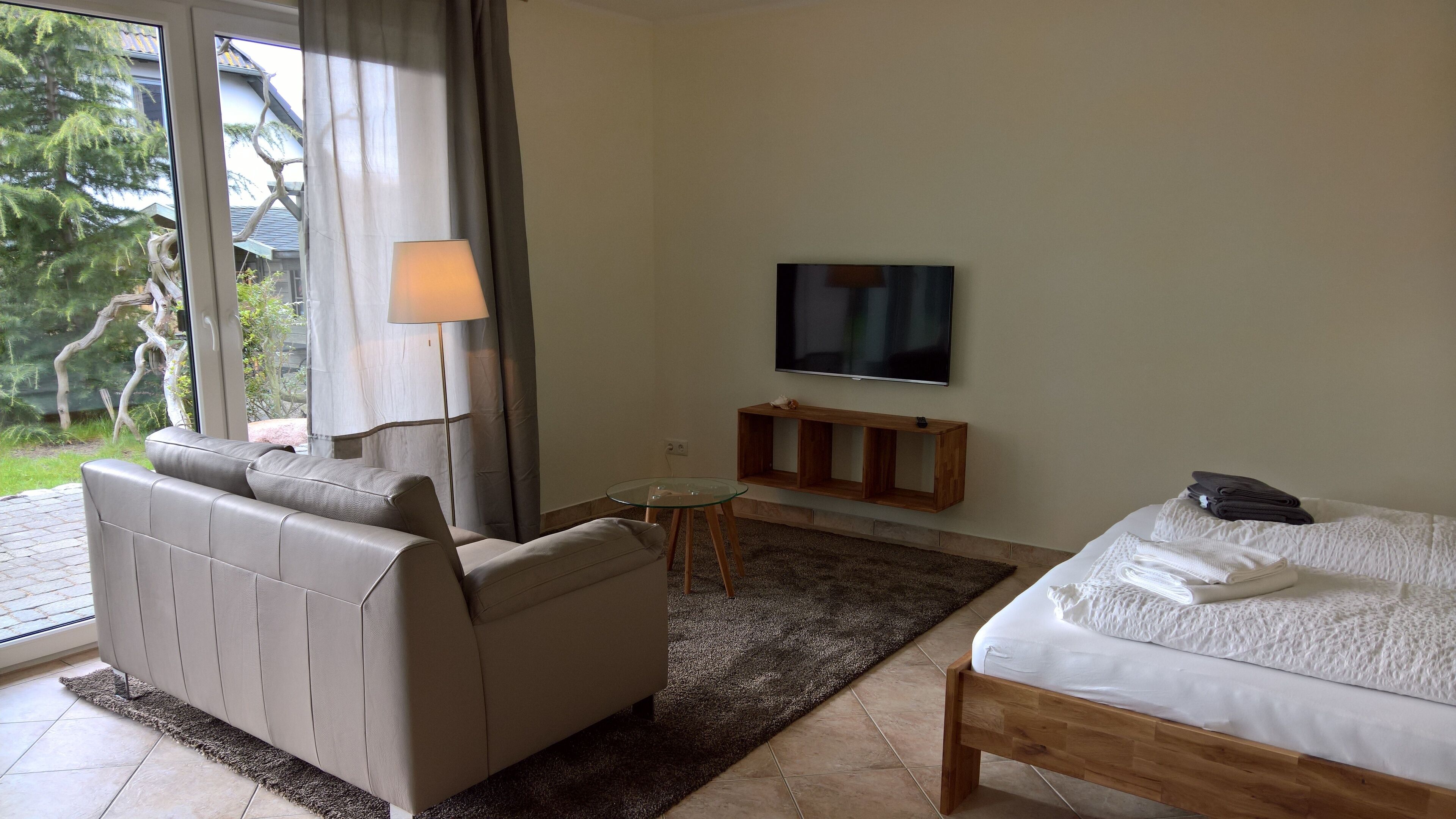 Een hotelkamer met een bank, een kleine tafel, een televisie en een bed.