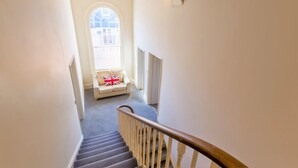 A staircase leading to a landing with a sofa and a flag cushion. - Luxury Apartments - Churchside (Cheltenham)
