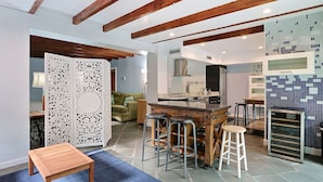A modern kitchen with a central island, bar stools, and a wooden table. - Private Heated Pool, Great Location by Pulaski Square in Historic District (Savannah)