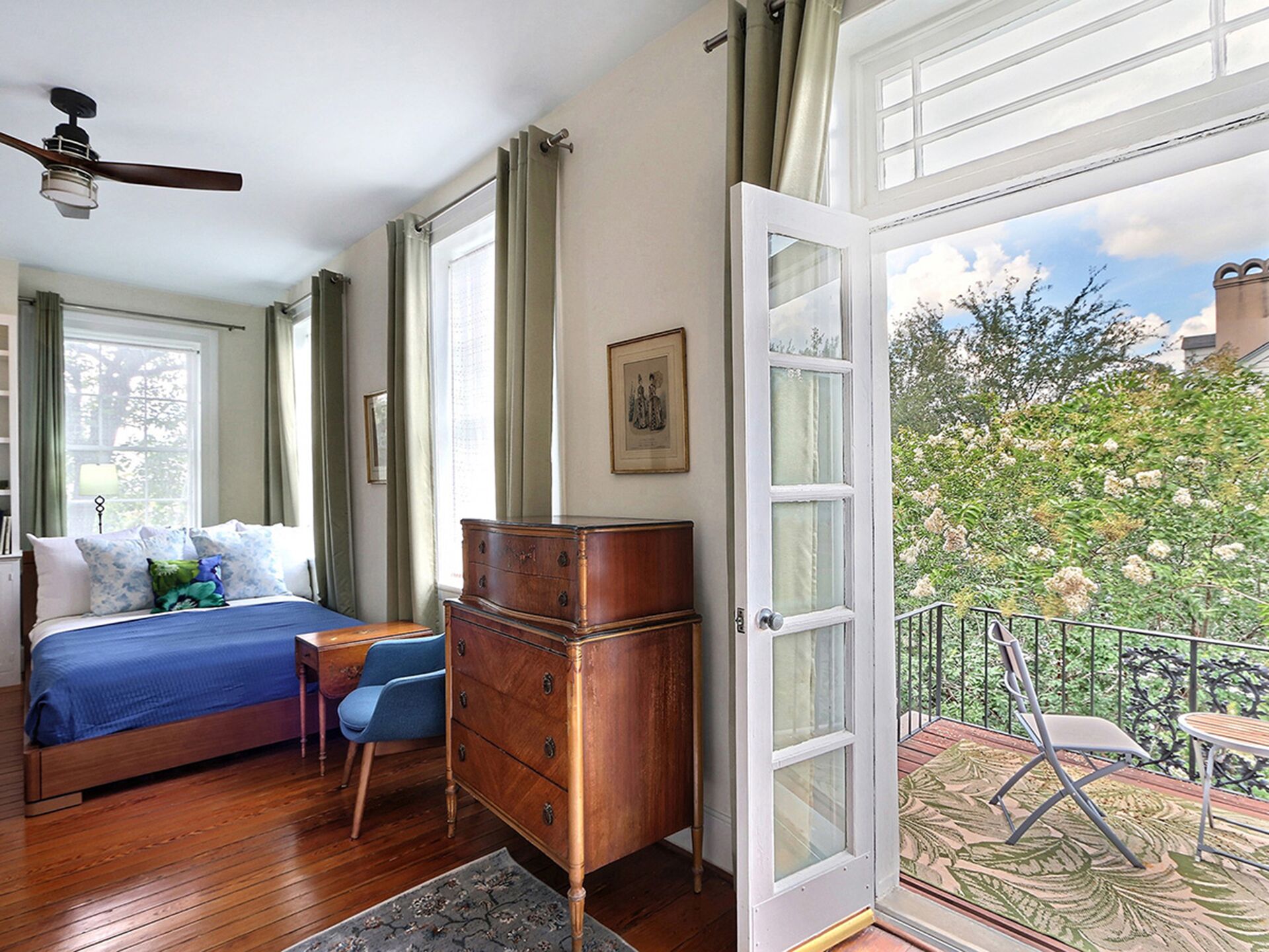 Un dormitorio con cama, cómoda y vistas a un balcón con mobiliario exterior.