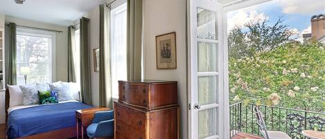 Un dormitorio con cama, cómoda y vistas a un balcón con mobiliario exterior.