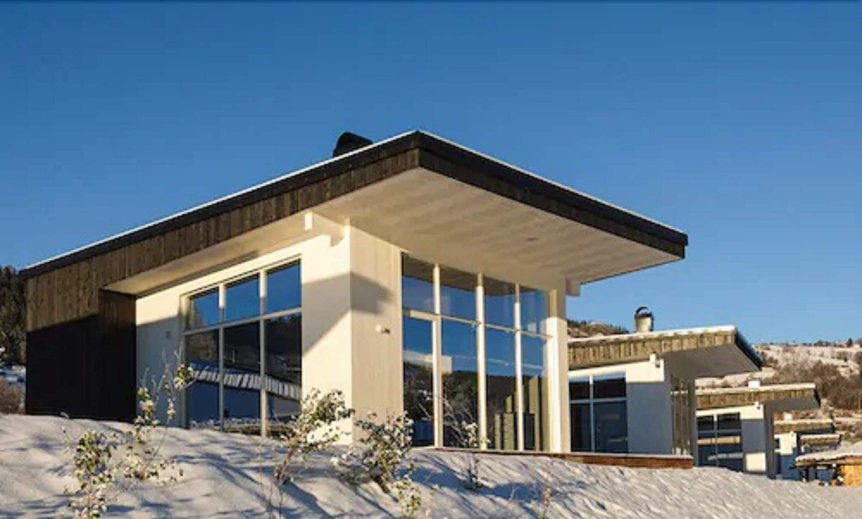 Un edificio moderno con ventanas amplias y techo plano, rodeado de nieve.