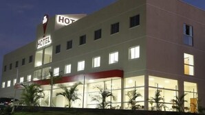 Un hotel de varios pisos con fachada plana, ventanas amplias y un llamativo letrero que dice 'HOTEL'.