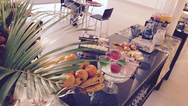Una mesa de buffet con frutas, bebidas y una licuadora.