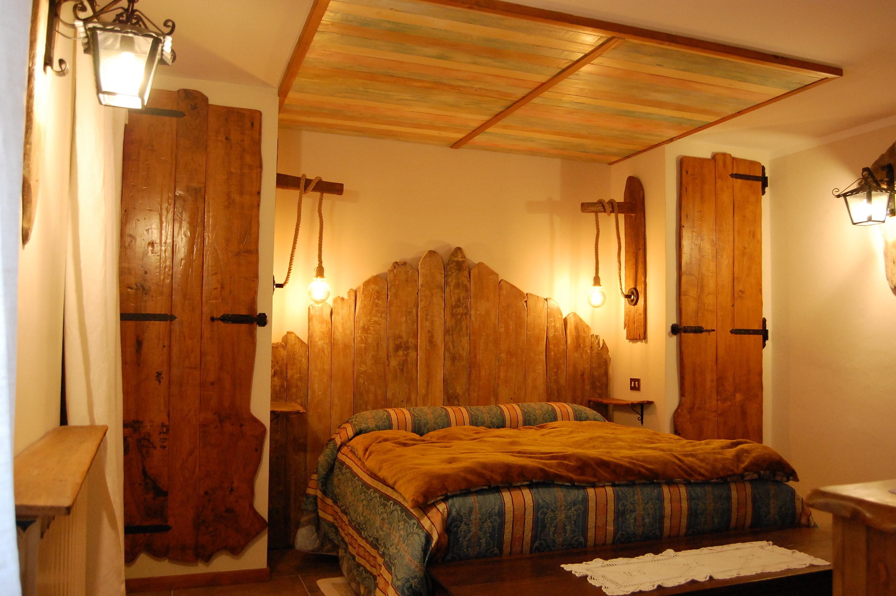 Een slaapkamer met een houten hoofdbord, twee bedlampen en een bed met een geborduurd sprei.