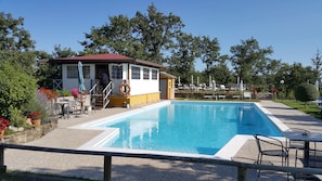 Une piscine équipée d’une bouée de sauvetage, d’un poste de surveillance pour les sauveteurs et de chaises longues.