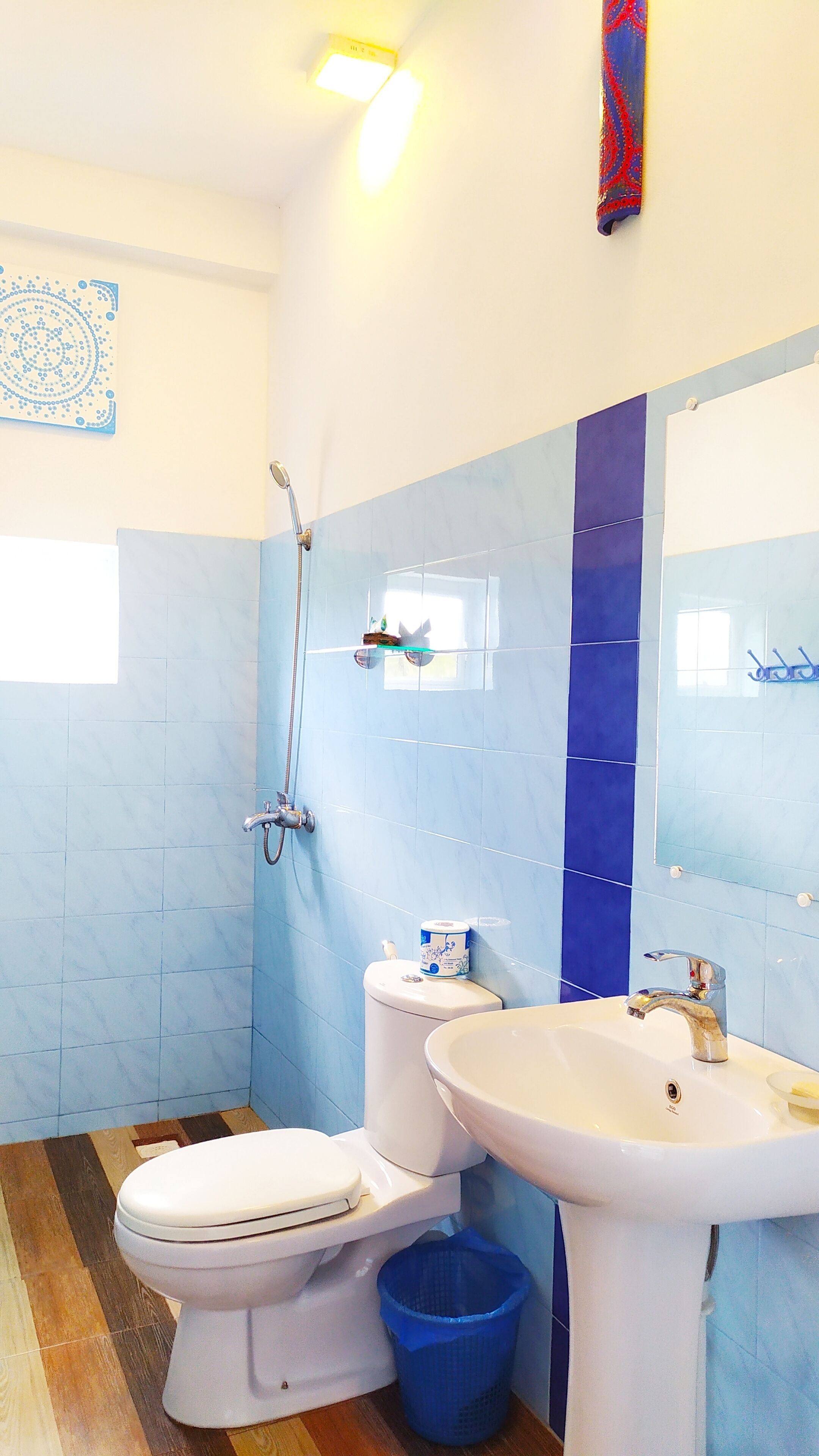 Bagno con toilette, bidet, lavabo e pareti piastrellate di blu.