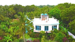 A white building with large windows and a balcony, surrounded by dense tropical vegetation. - Villa Modara (Kahandamodara)