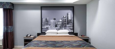 Habitación de hotel con cama, un cartel de paisaje urbano en la pared, un teléfono y un reloj en la mesita de noche.