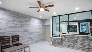 A modern room with a marble wall, a wooden bench, a ceiling fan, and a window with a view. - Super 8 by Wyndham Humble/Fallcreek/Houston (Humble)
