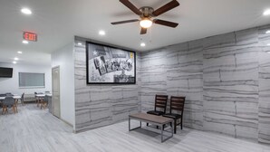 A conference room with a marble wall mural, a ceiling fan, and a table with chairs. - Super 8 by Wyndham Humble/Fallcreek/Houston (Humble)