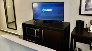 A hotel room with a flat-screen TV displaying DIRECTV, a microwave, and a small table with a coffee maker. - Wingate by Wyndham JFK Airport/Far Rockaway (Far Rockaway)