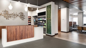 Un área de recepción moderna con un mostrador de madera, una lámpara de pared y una máquina expendedora.