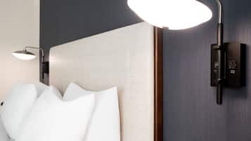 A modern bathroom with a large, white, sculptural headboard, a wall-mounted light fixture, and a sleek, dark-colored panel.