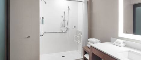 A modern bathroom with a walk-in shower, a vanity with a mirror, and a towel rack.
