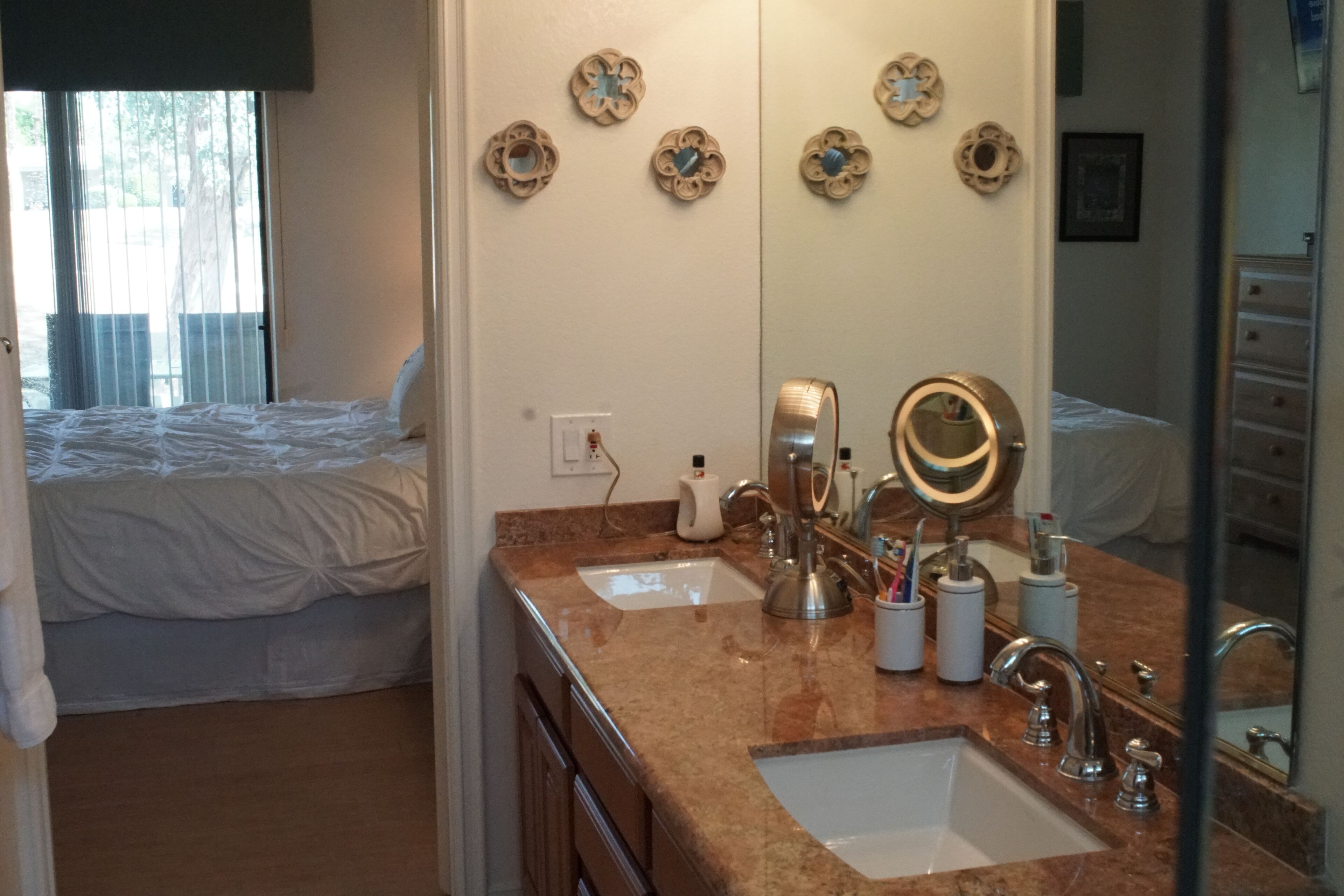 Camera d'albergo con un letto matrimoniale, bagno con doppio lavabo, uno specchio grande e decorazioni a parete.