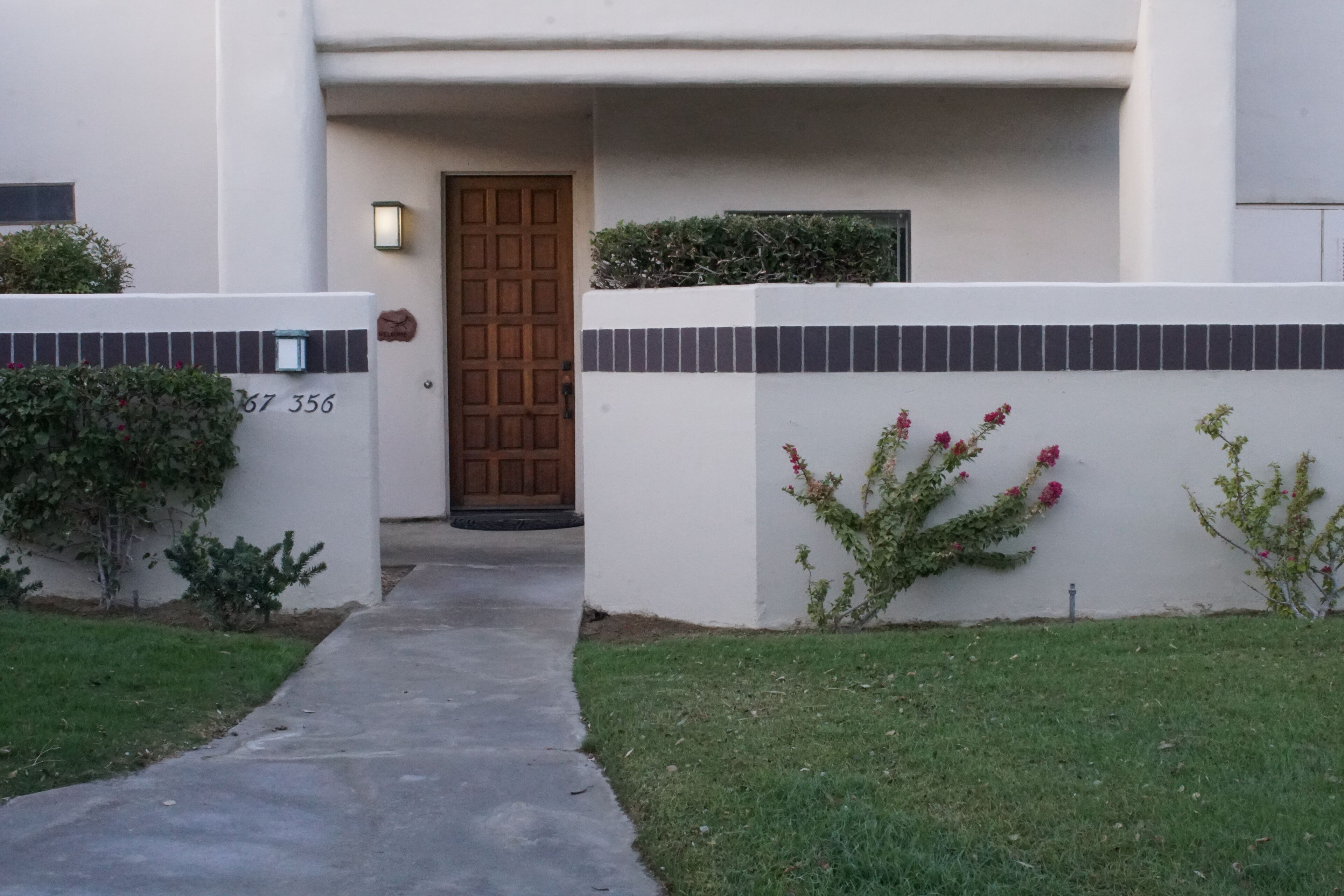 A modern house with a concrete pathway leading to a wooden door.