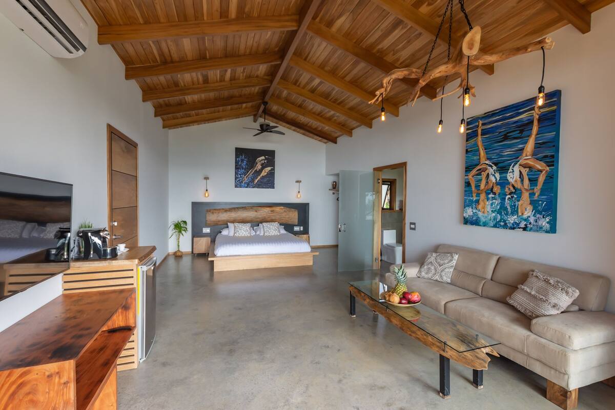Una sala de estar moderna con techo de madera, una cama, un sofá y un comedor.