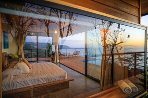 Une chambre moderne avec un grand lit, une terrasse en bois et une vue sur la mer.