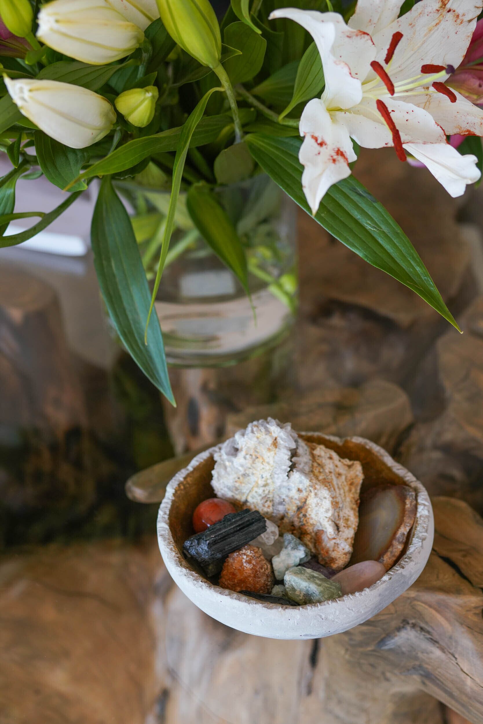 A small bowl with various items on a wooden surface.