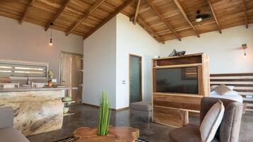 Un vaste espace de vie doté d’un plafond haut, d’un plafond en bois, d’un grand téléviseur, d’un coin salon confortable et d’un comptoir de cuisine.