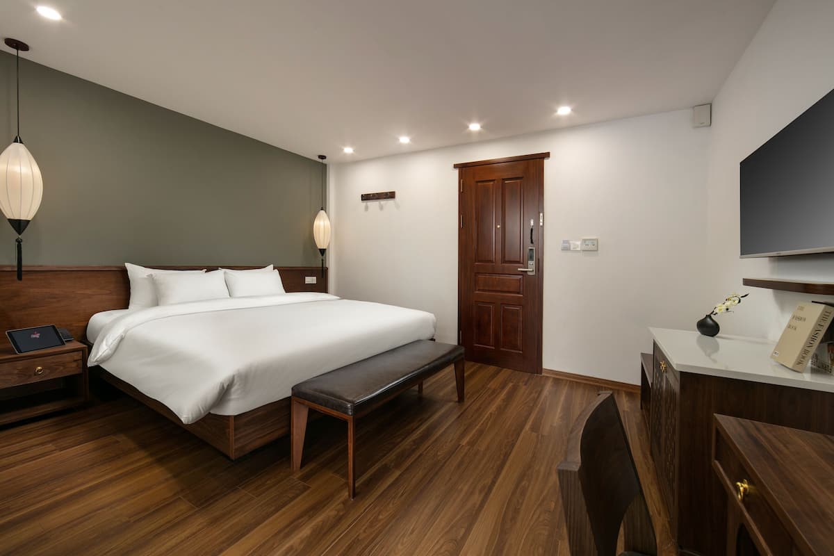 A neatly arranged bedroom with a bed, bedside tables, a bench, a desk, and a wardrobe.