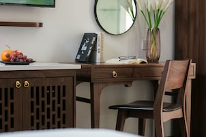 A wooden desk with a laptop, books, and a vase of flowers.