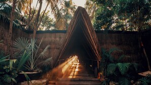 A thatched-roof structure with a pathway leading through it, surrounded by tropical plants. - Radhoo Tulum (Tulum)
