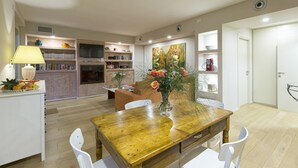 Une cuisine moderne avec un coin repas, une table en bois, des chaises blanches et un vase rempli de fleurs.