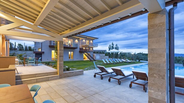 A modern outdoor patio with a pool, lounge chairs, and a covered seating area.