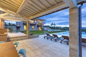 Une terrasse extérieure moderne dotée d’une piscine, de chaises longues et d’un espace salon abrité.