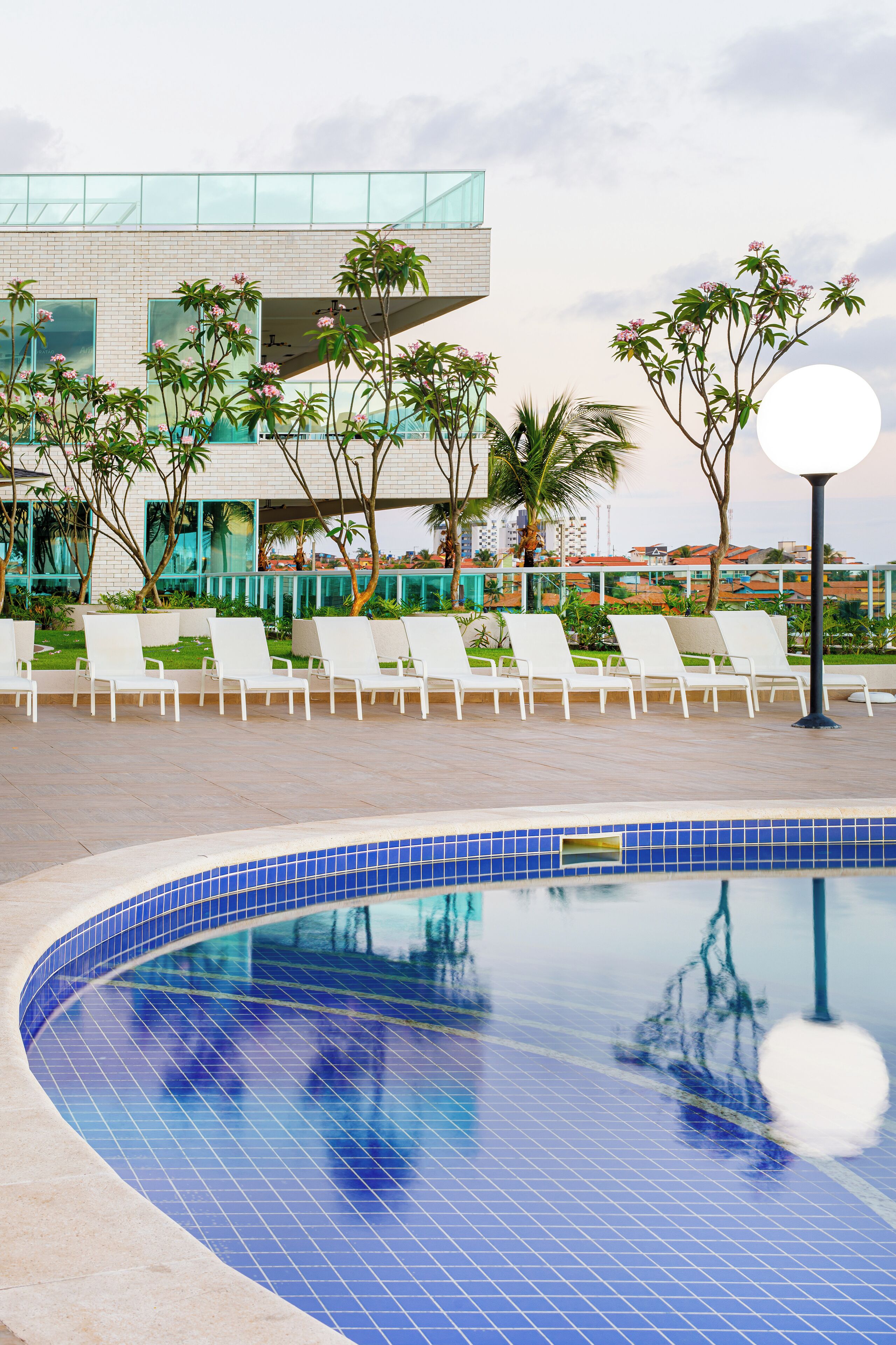 A modern pool area with lounge chairs and a clear view of a building with large windows and a glass facade.