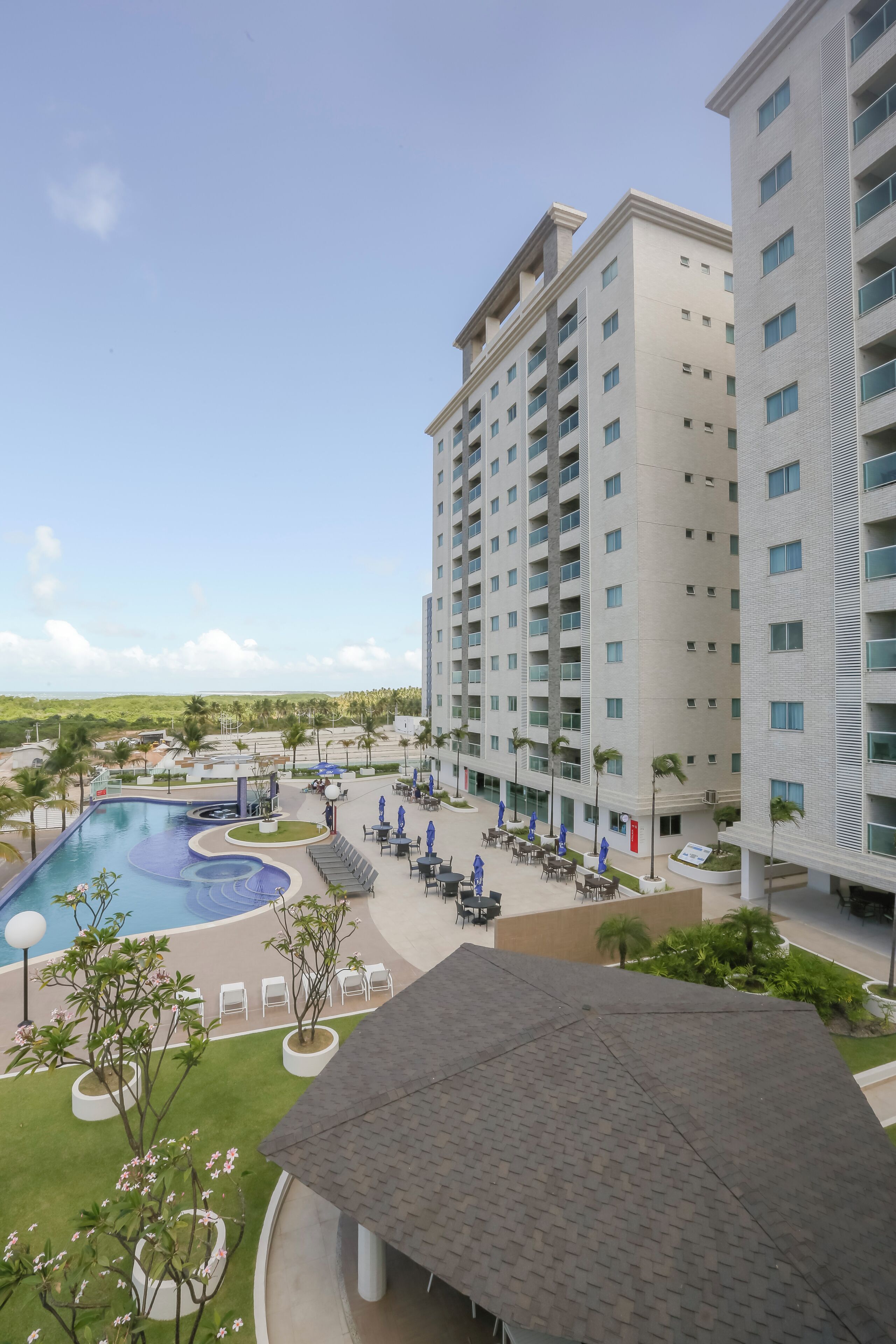 A hotel with a swimming pool, outdoor seating, and a view of the surrounding landscape.