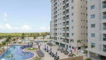 A hotel with a swimming pool, outdoor seating, and a view of the surrounding landscape.