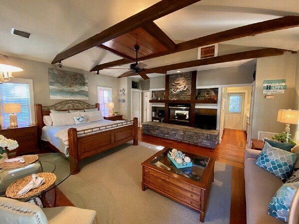 A spacious living room with a large bed, a fireplace, a coffee table, and a sofa.
