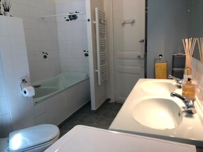 Bathtub, hair dryer, towels, toilet paper