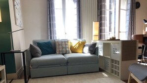 Una sala de estar con un sofá gris, cojines estampados, una mesita auxiliar y una silla.
