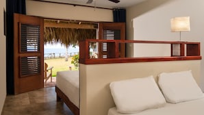 A bedroom with a bed, a ceiling fan, a nightstand, and a view of a beach through open doors. - Hotel Bocaino (San Rafael del Yuma)