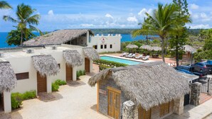 A resort with thatched-roof buildings, a swimming pool, and a view of the ocean. - Hotel Bocaino (San Rafael del Yuma)
