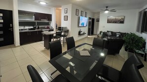 Un apartamento moderno con comedor, cocina, sala de estar y televisor.