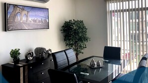 Un espacio de oficina moderno con una mesa de vidrio, sillas de cuero negro, una planta en maceta y un cuadro con una imagen de un puente.