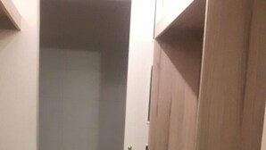 A narrow hallway with a wooden floor leading to a small bathroom containing a toilet and a rug. - GL Apts, rent Upper Pardo Miraflores (Miraflores)