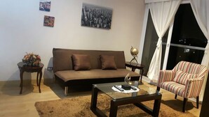 A living room with a brown sofa, a striped armchair, a glass coffee table, and a small side table with a lamp. - GL Apts, rent Upper Pardo Miraflores (Miraflores)