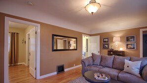 A living room with a brown sofa, a coffee table, and a mirror on the wall. - Charming home near Boise State and The Train Depot
 (Boise)