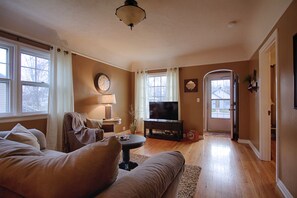 A living room with a sofa, a television, a lamp, and a window with curtains.