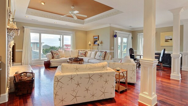 A spacious living room with a high ceiling, large windows, and a view of the outside. - Heated Pool Access | 5*Clean | Flex Cancelation (Tybee Island)