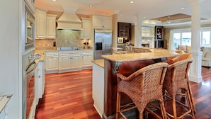 A spacious kitchen with white cabinetry, a large island with bar stools, and a central island with a built-in sink. - Heated Pool Access | 5*Clean | Flex Cancelation (Tybee Island)