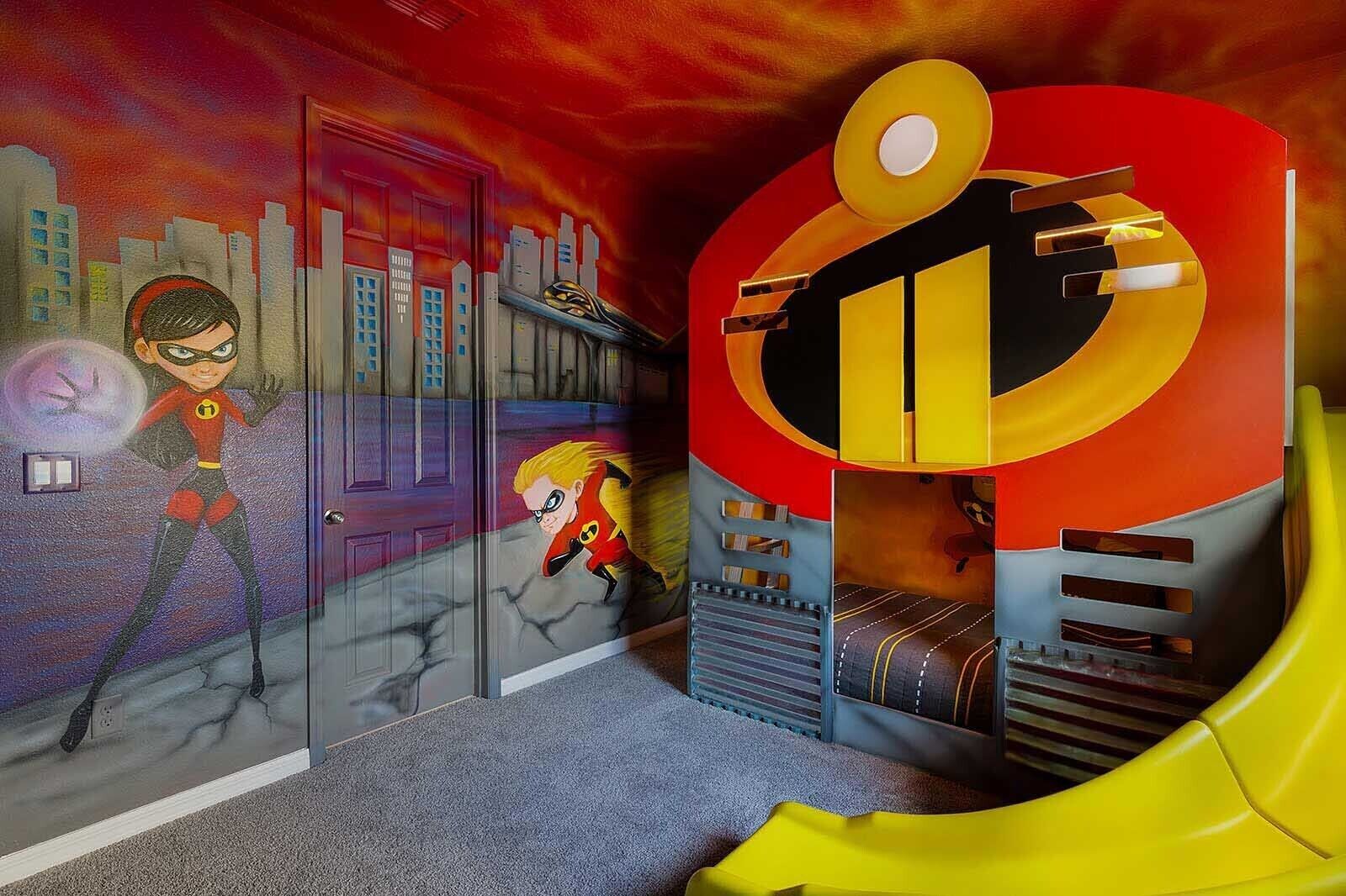 A children's playroom with superhero-themed murals, a slide, and a play area.